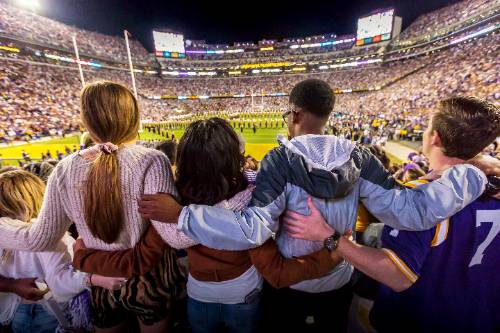 Students sing the alma mater at a football game.