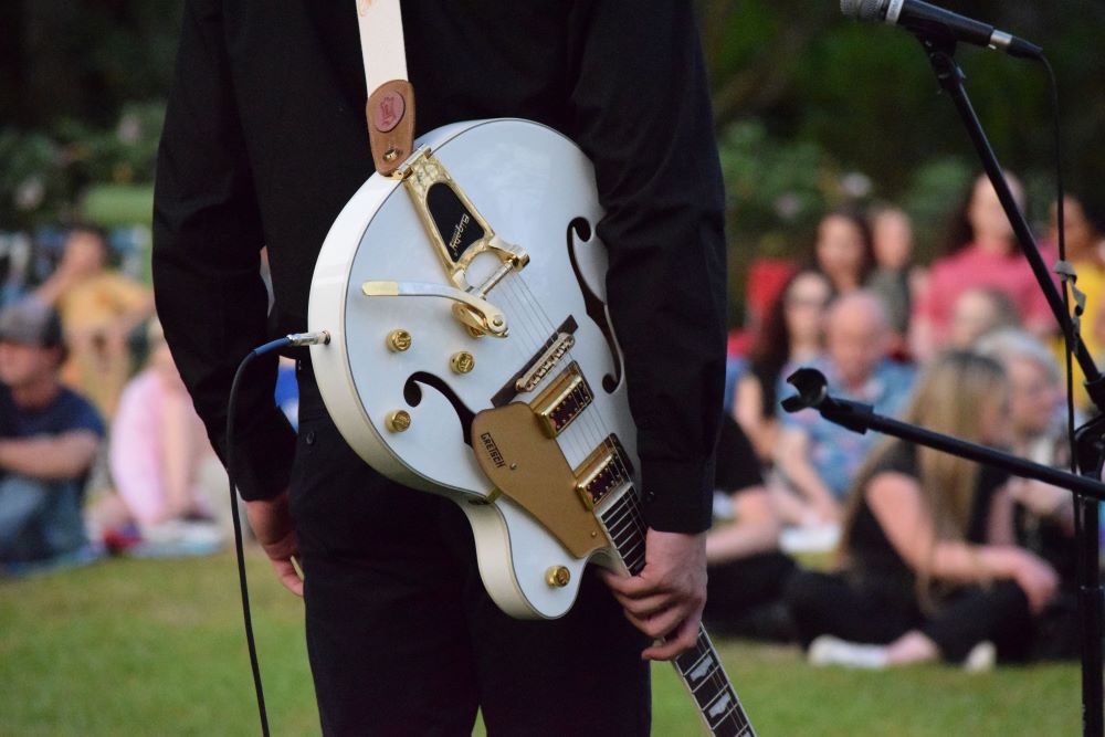 musician holding guitar at Music in the Gardens