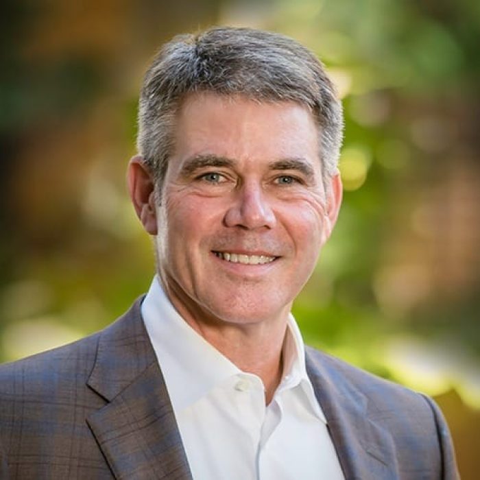 Roy Martin wears a dark suit jacket and smiles for a headshot. 