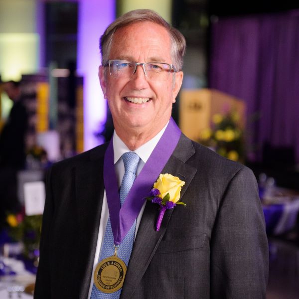 Kip Knight is wearing a suit and a medal around his neck. 