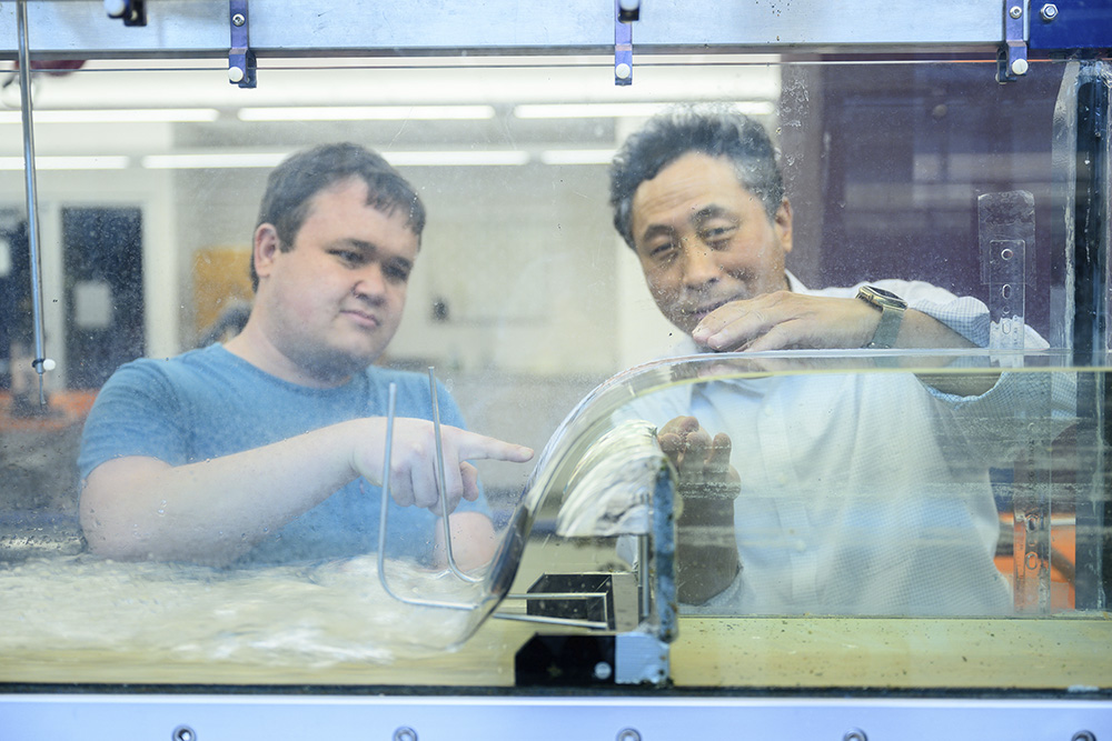 Professor and student look inside water flow device