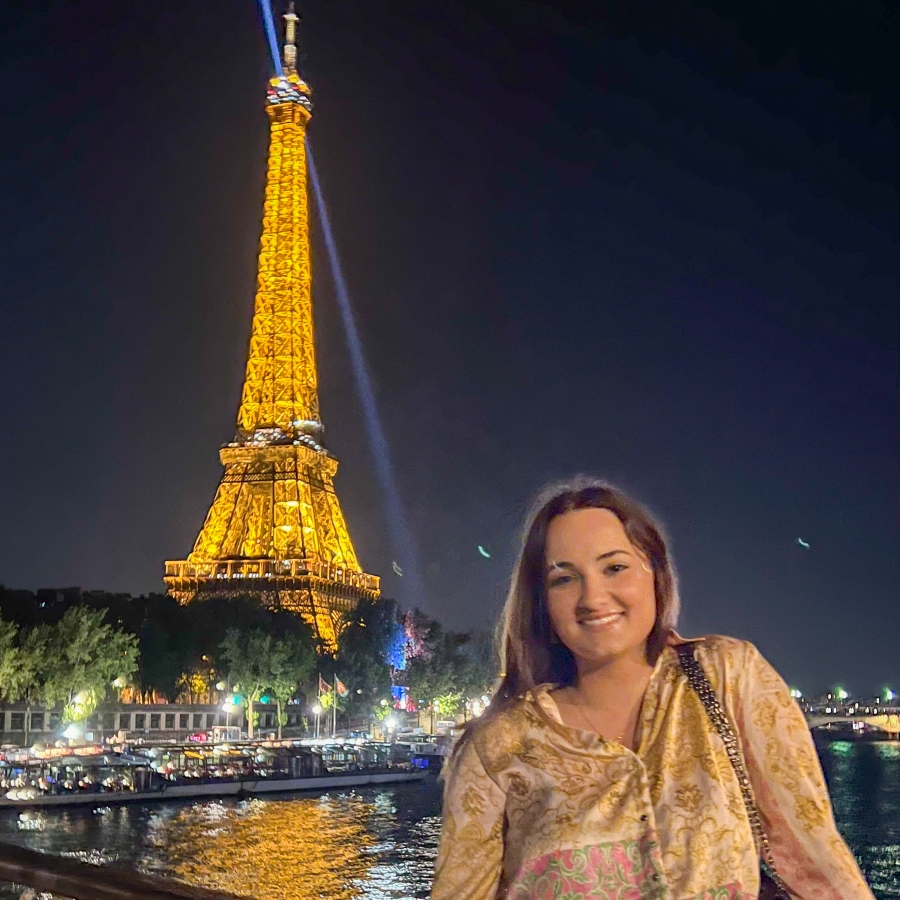 student smiles in front of the Eiffel Tower