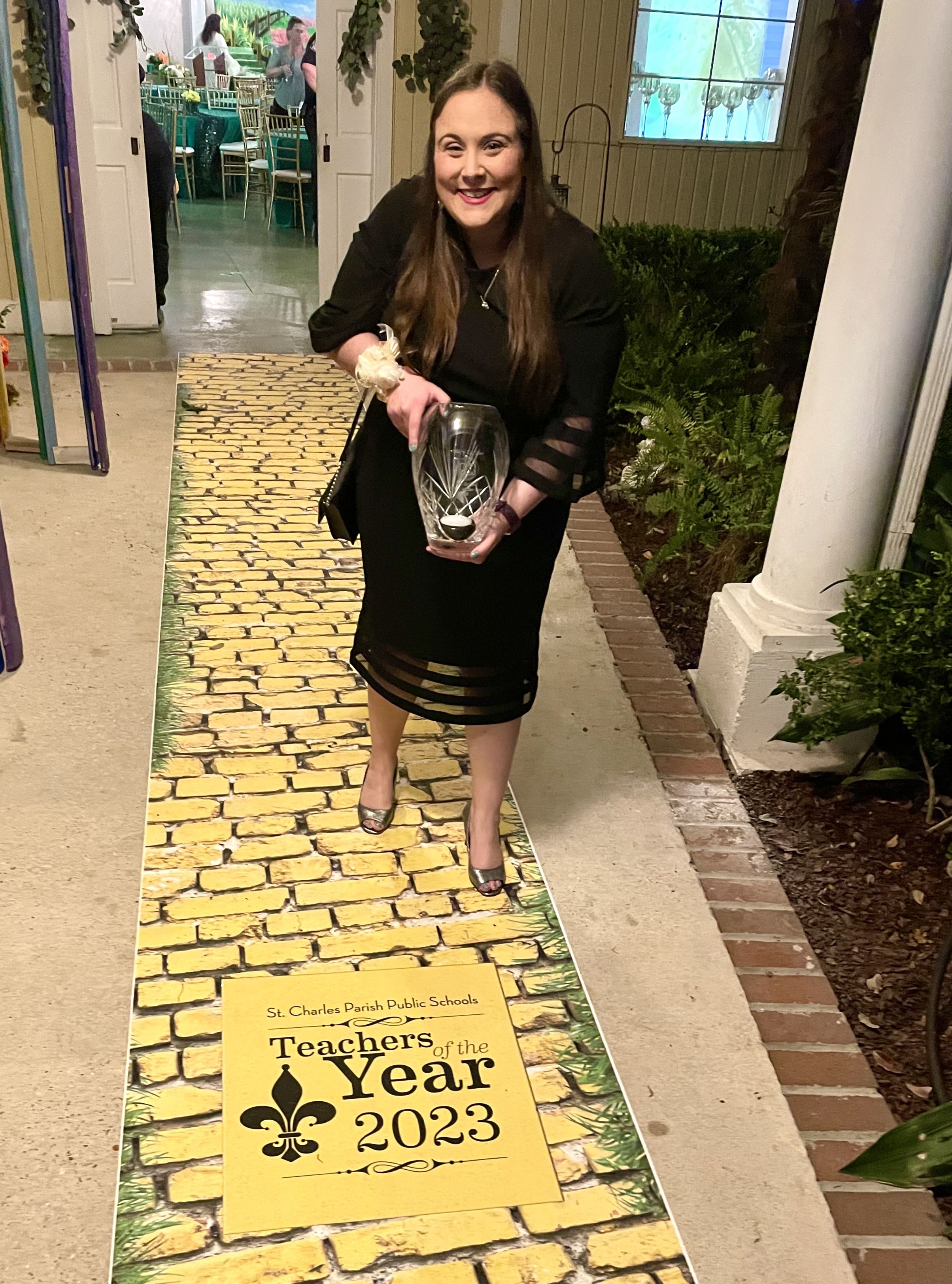 Macy holding a glass award for District Teacher of the Year