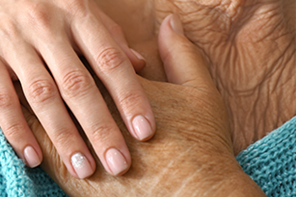 Caregiver holding the hand of an older adult