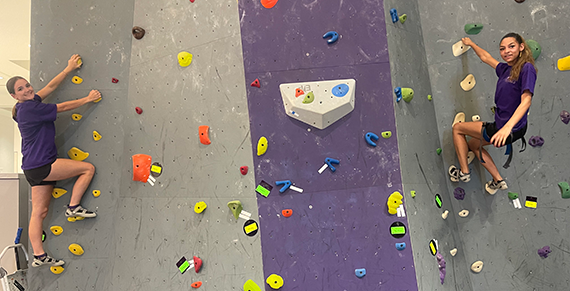 Shaping Futures participants climbing the indoor UREC rock wall during a program activity.